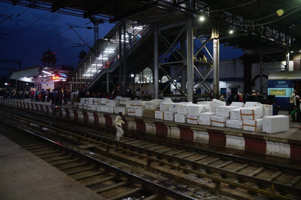 Viele weiße Pakete stehen neben dem Gleis