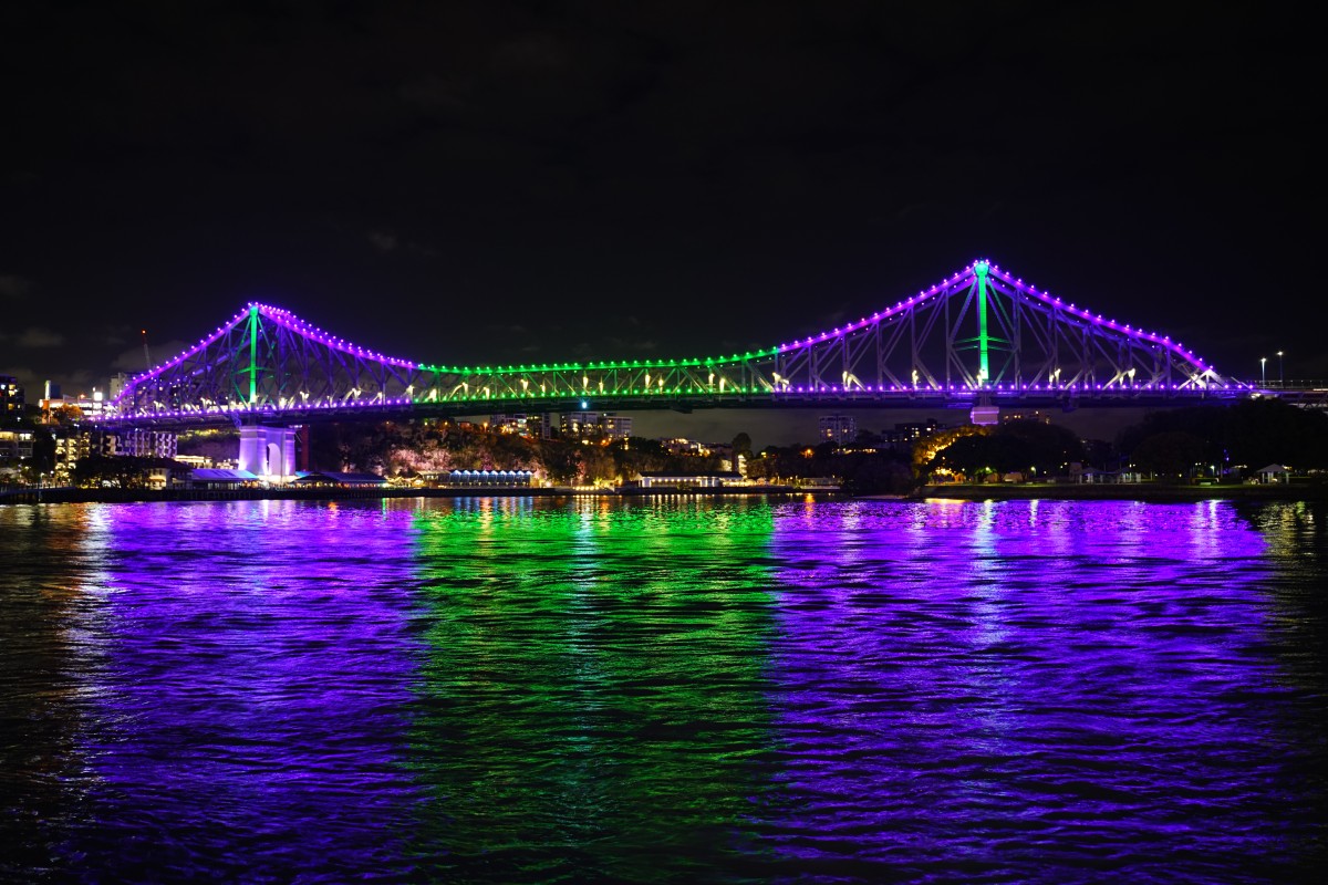 Die Story Bridge mit ihrer lila-grün-lila Beleuchtung spiegelt sich im Brisbane River