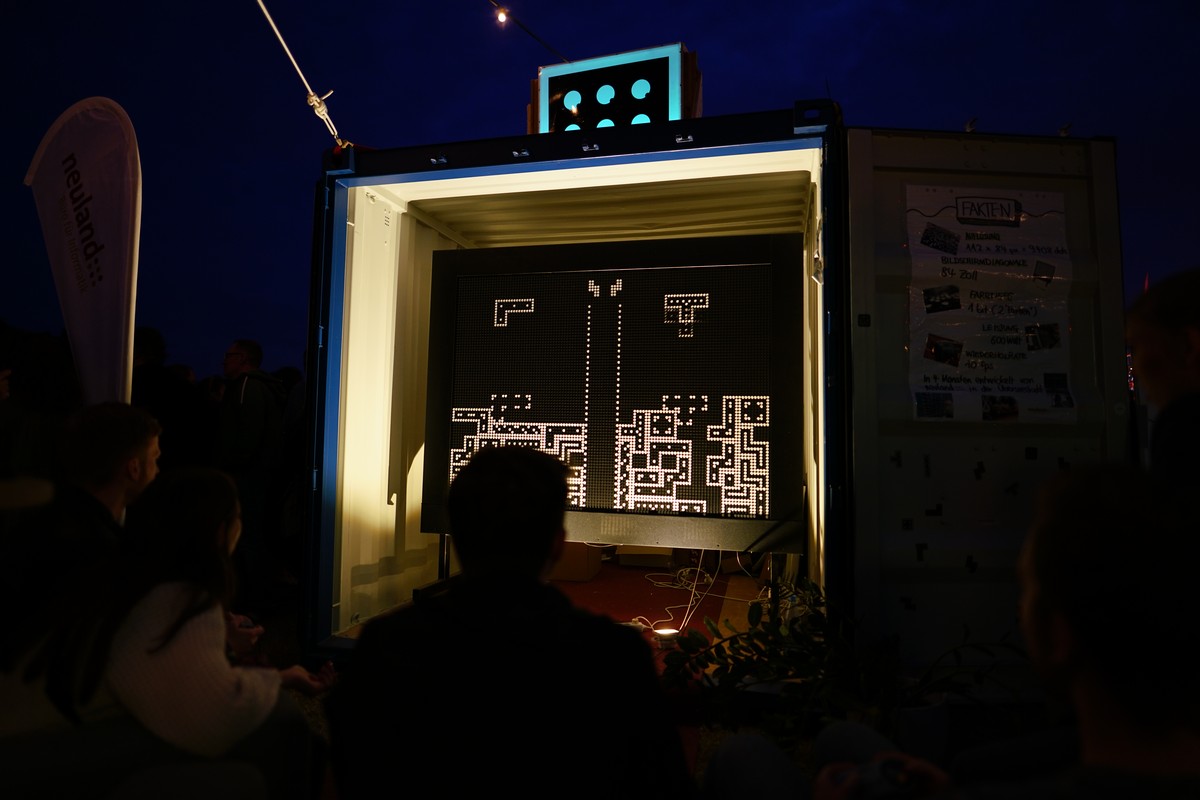 Leute spielen gegeneinander Tetris auf einem großen Flip-Dot-Display