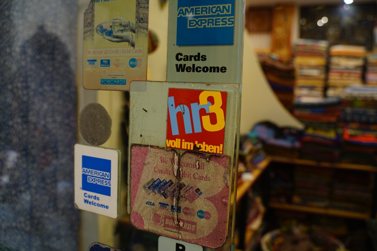 Ladentür mit Kreditkartenakzeptanzsymbolen und einem Aufkleber des Radiosenders hr3