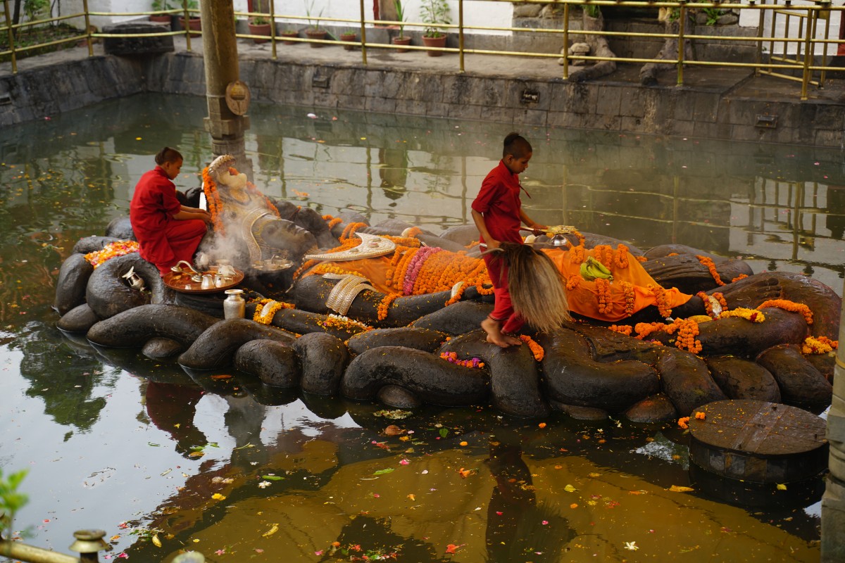 Kinder reinigen ein steinernes Kultbild von Vishnu