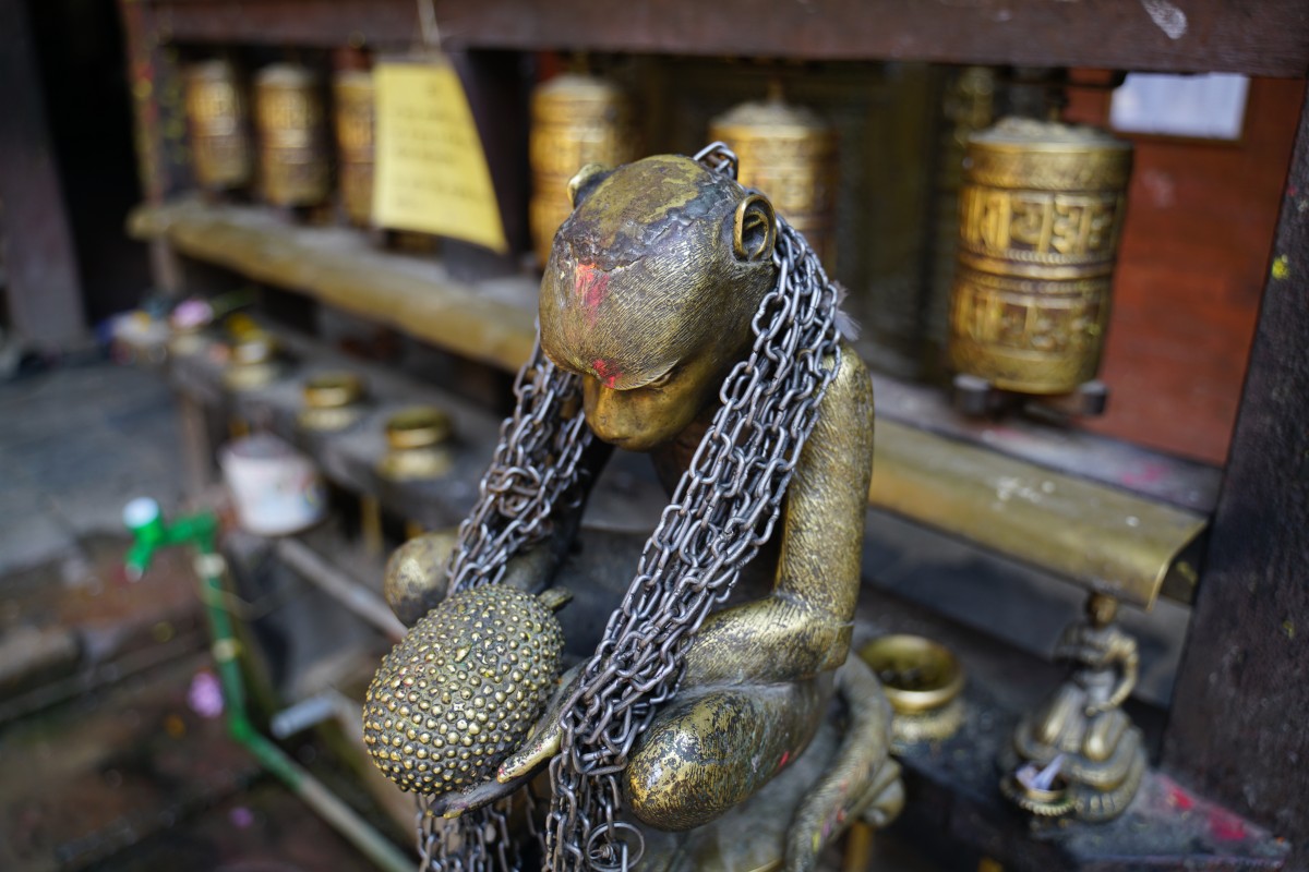 Statue eines Affen, der einen Schnabeligel in der Hand hält und anstarrt