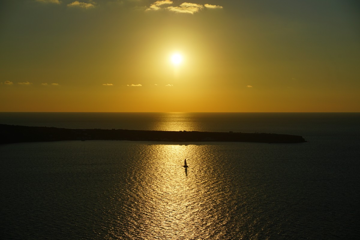 Kleines Segelboot vorm Sonnenuntergang