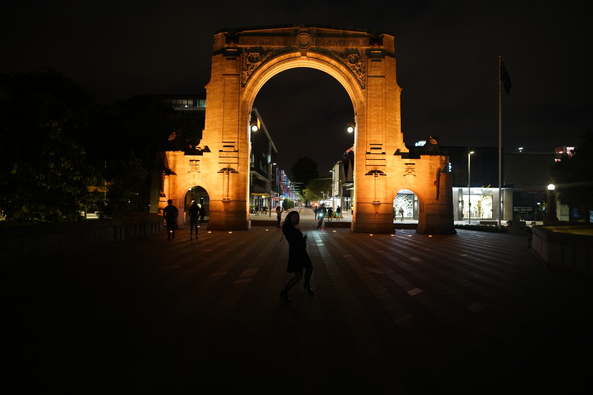 Eine Frau posiert nachts vor der Bridge of Remembrance