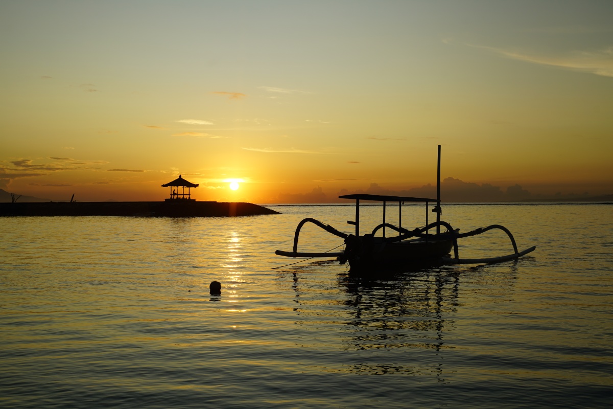 Typisch indonesisches Boot Jukung im Sonnenaufgang bei Pantai Karang in Sanur auf Bali