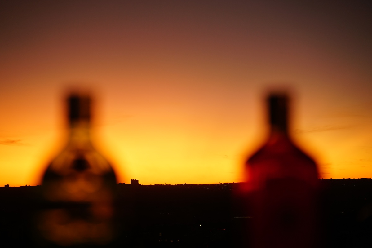 Blick von der Dachterrasse des Radisson Red Rosebank auf das Northcliff im Sonnenuntergang, im Vordergrund zwei Flaschen