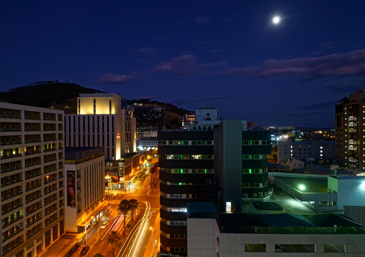 Strand St in Kapstadt morgens in der Blauen Stunde im Mondschein, hinten links der Signal Hill