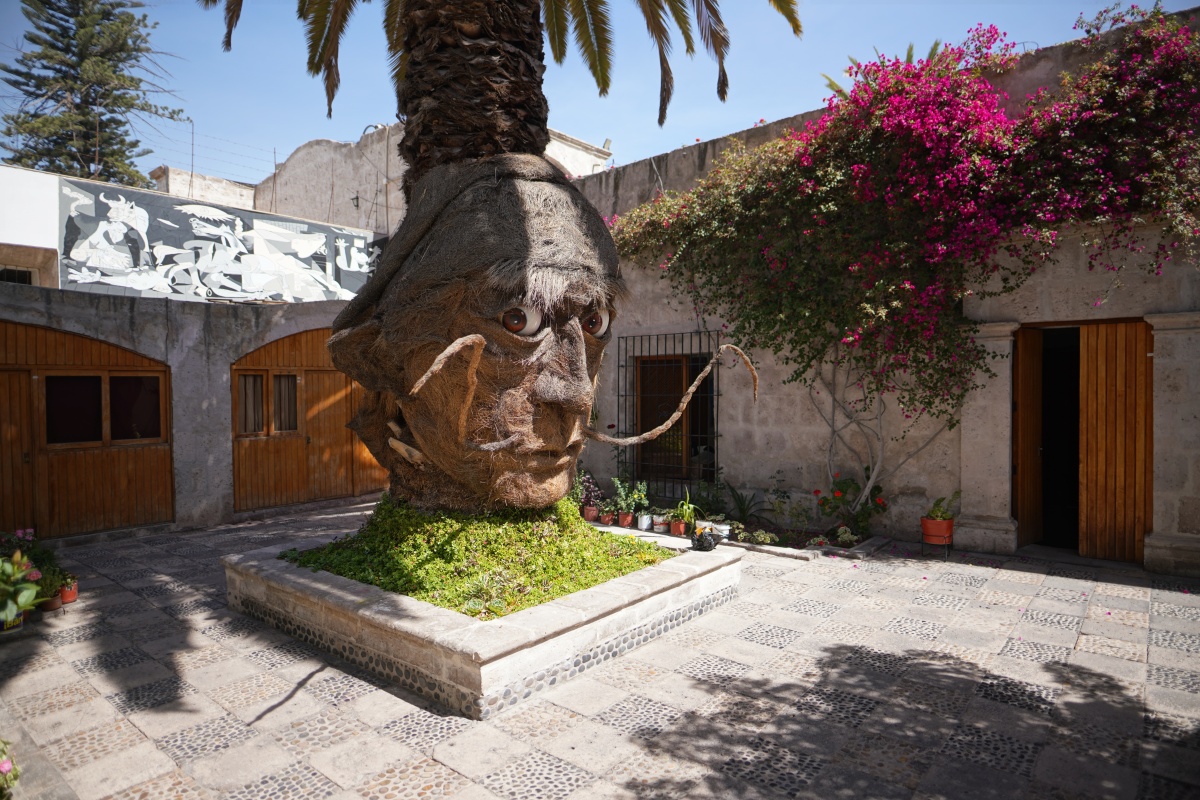 Figur am Fuße einer Palme im Complejo Cultural UNSA in Arequipa