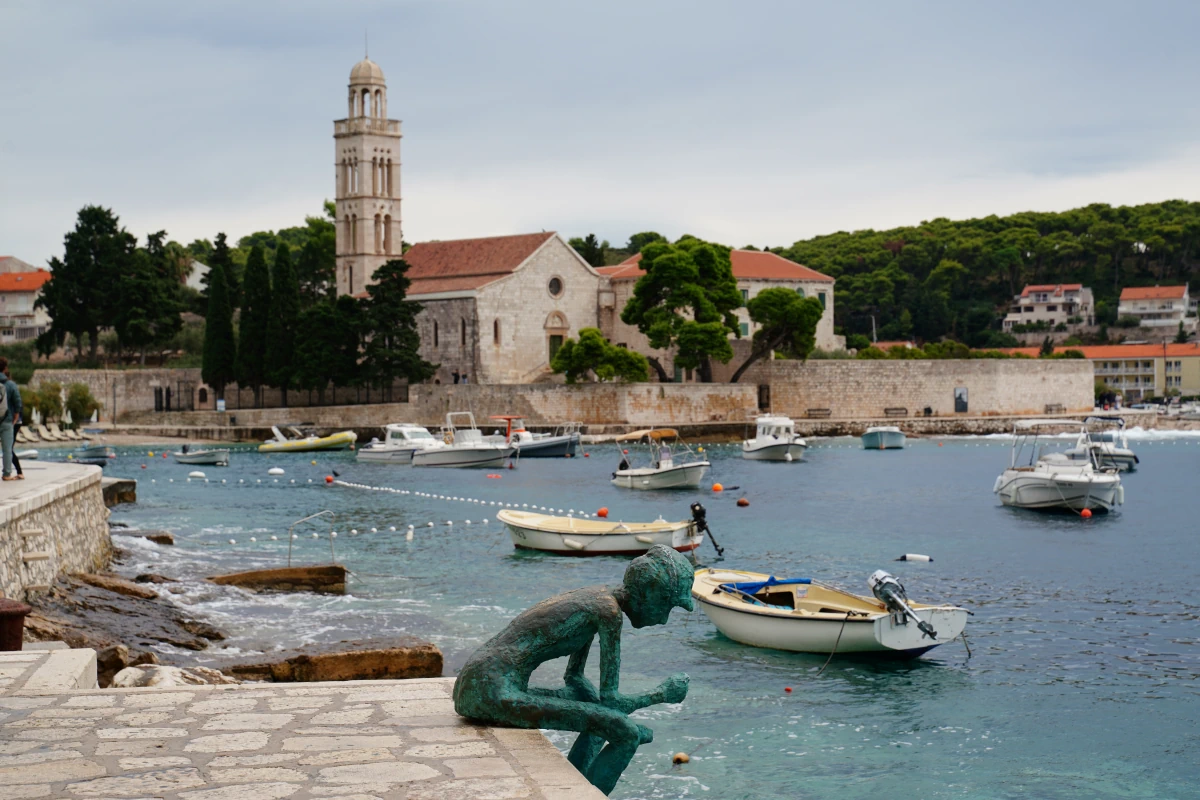 Skulptur Bata Duje, dahinter das Franziskanerkloster von Hvar-Stadt