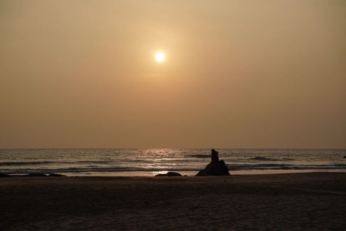 Beach Boy auf einem Stein im Sonnenuntergang in Bentota